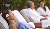 A woman with a flower in her hair relaxes on a padded chaise lounge in a spa area
A woman with a flower in her hair relaxes on a padded chaise lounge in a spa area