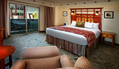 A sliding balcony door near a king bed with 2 night stands across from a chaise lounge
A sliding balcony door near a king bed with 2 night stands across from a chaise lounge