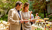 A man and a woman each hold plates with food as they walk along a buffet line
A man and a woman each hold plates with food as they walk along a buffet line