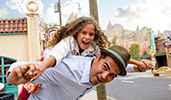 A smiling child on the back of a man in Cars Land at Disney California Adventure Park A smiling child on the back of a man in Cars Land at Disney California Adventure Park
