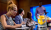 A woman works on her tablet as 2 coworkers talk to a man at a conference table
A woman works on her tablet as 2 coworkers talk to a man at a conference table
