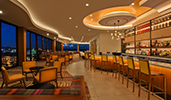 A lounge with a full bar with stools, cocktail tables with padded chairs and a Magic Kingdom Park view
A lounge with a full bar with stools, cocktail tables with padded chairs and a Magic Kingdom Park view