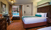 A room featuring a bed with a headboard and overhead sconce, drawers, an ice bucket and glasses, a desk, a chair, a window with a pool view and more A room featuring a bed with a headboard and overhead sconce, drawers, an ice bucket and glasses, a desk, a chair, a window with a pool view and more