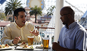Men seated at an outdoor table with glasses of beer and plates of food Men seated at an outdoor table with glasses of beer and plates of food