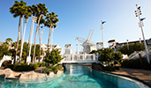 A bridge over a pool with steps and a railing in an outdoor setting featuring trees and more A bridge over a pool with steps and a railing in an outdoor setting featuring trees and more