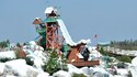 A hillside in Disney’s Typhoon Lagoon water park with water flowing over rocks into a lagoon and a replica shipwrecked atop a crag