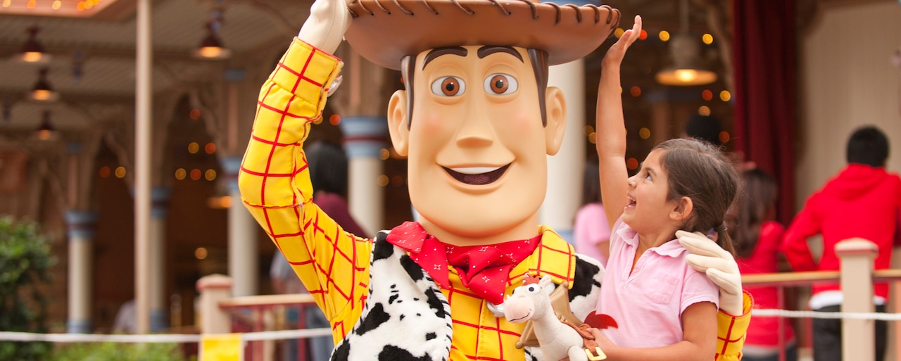 El personaje Woody interactúa con una niña que le toca su sombrero de vaquero y trae un caballo de juguete Bullseye