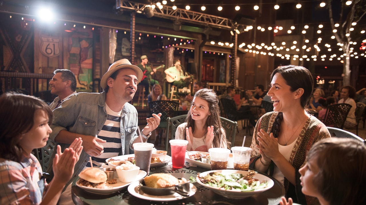 A family enjoys dinner at a Disney Springs restaurant while a live band plays music in the background