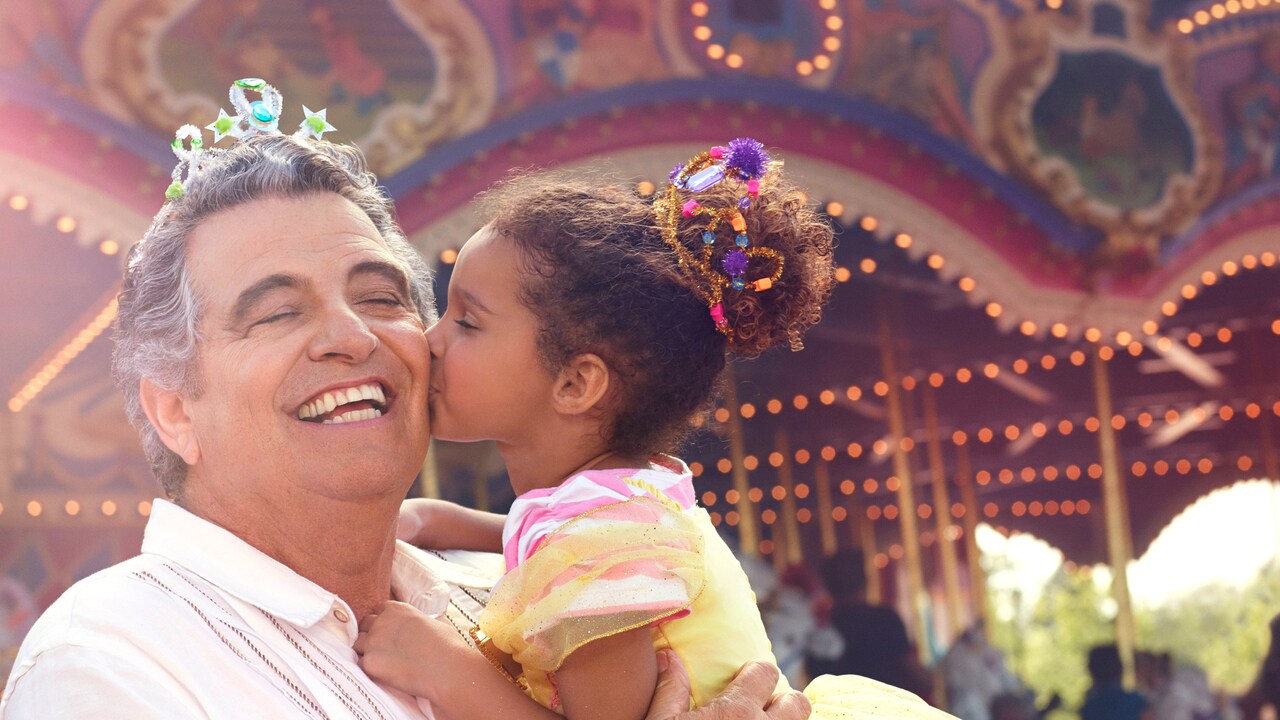 Prince Charming Regal Carrousel spins as a young female Guest kisses her grandfather on the cheek