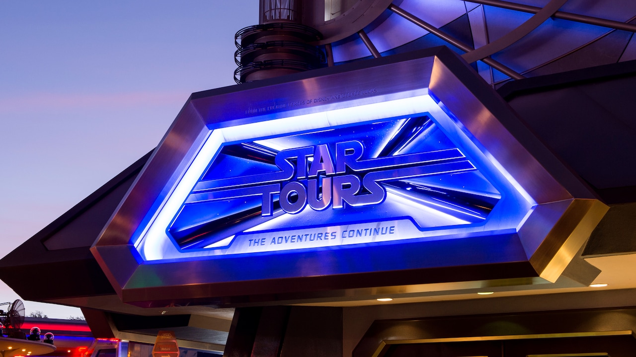 Un letrero iluminado de noche señala la atracción Star Tours The Adventures Continue