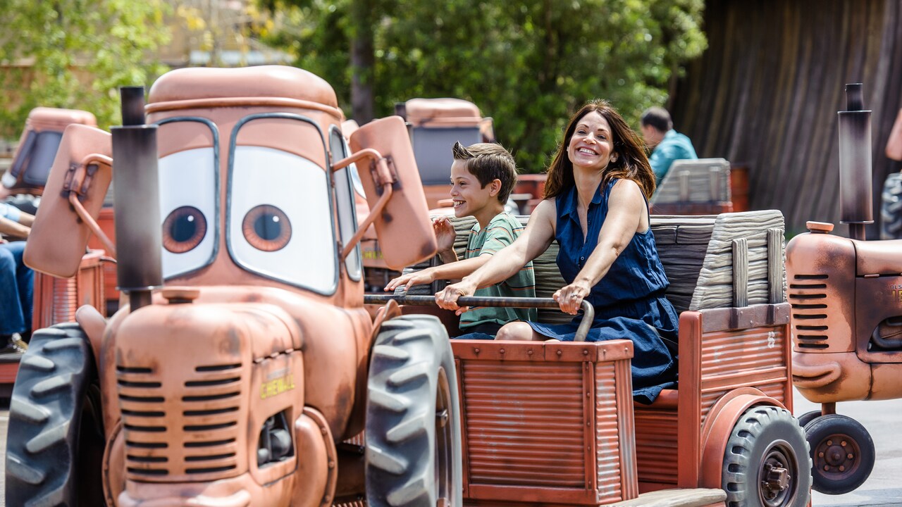 Una mamá pasea con su hijo en remolque, en la atracción Mater's Junkyard Jamboree