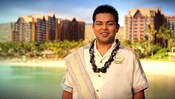 A Cast Member poses with Aulani, A Disney Resort & Spa in Ko Olina, Hawai'i in the background