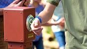 A Guest puts his MagicBand up to a touchpoint in a Disney Park