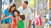 A mother shows the rest of her family her cell phone inside a Disney theme park