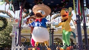 Donald Duck entertains on stage with Panchito the rooster and José Carioca the parrot