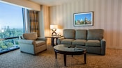 Living room seating area with sofa opened out to a double bed, occasional table and lamp and upholstered chair