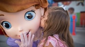 A little girl gives Disney's Princess Sophia a kiss on the cheek, at Walt Disney World Resort
