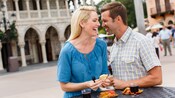 A couple enjoys food and wine at an outdoor table in Epcot’s Italy Pavilion at Walt Disney World Resort