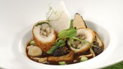 A stuffed chicken dish garnished with truffle foam and served in a mushroom truffle ragu