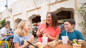 A smiling mother and daughter enjoy meals at an outdoor table A smiling mother and daughter enjoy meals at an outdoor table