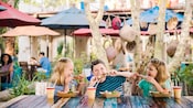 Trois enfants savourent des brochettes de poulet et des boissons à une table extérieure Trois enfants savourent des brochettes de poulet et des boissons à une table extérieure
