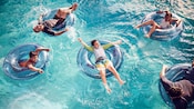 Five Guests float on inner tubes in a pool Five Guests float on inner tubes in a pool