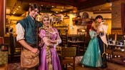 Rapunzel and Flynn Rider standing in a dining room while Ariel and Prince Eric dance nearby