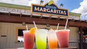 A row of four assorted beverages in front of the pickup window at Dockside Margaritas