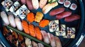 Large, round plate featuring a wide assortment of elegant sushi and sashimi offerings