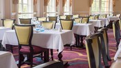 A dining room filled with tables and ornately displayed table settings inside Monsieur Paul at Epcot