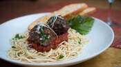 Plate with 2 large meatballs atop marinara sauce and spaghetti
