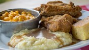 A 2-piece fried chicken dinner plated with a mashed potatoes & gravy, macaroni & cheese and cornbread
