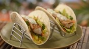 A duo of tacos in flour tortillas with lettuce, carrots, cilantro and freshly grilled pieces of fish
