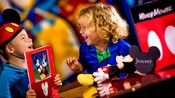 Two little kids share their enjoyment of a Mickey and Minnie picture book