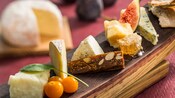 Assorted fruits and cheeses atop a wooden board