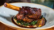 A lamb shank served atop wilted spinach