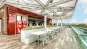 The covered outdoor Coca Cola rooftop beverage bar featuring a seating area, a service counter and Coca Cola Freestyle machines