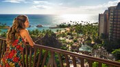 A woman on a balcony overlooking Aulani and the beach A woman on a balcony overlooking Aulani and the beach