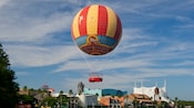 A helium balloon covered with classic flying Disney characters hovers over Downtown Disney area