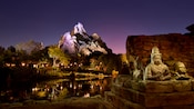 Asian statues and towering Forbidden Mountain at night in Disney's Animal Kingdom Theme Park