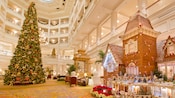 An ornately decorated holiday tree towering several stories beside an enchanting miniature house