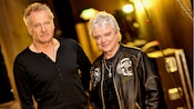 Band members from Air Supply standing together in a stadium hallway filled with tour equipment