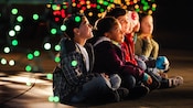 Dots of colorful lights swirling around wide-eyed children sitting crossed-legged