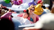 A mother, with her daughter sitting in her lap, ride Dumbo the Flying Elephant