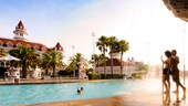 Des enfants nagent et s’amusent dans la piscine du Grand Floridian Resort pendant que leurs parents leur font signe et les regardent depuis le bord. Des enfants nagent et s’amusent dans la piscine du Grand Floridian Resort pendant que leurs parents leur font signe et les regardent depuis le bord.