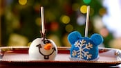 Holiday-themed cake pops on a tray, decorated like Olaf the snowman and a snowflake with Mickey ears