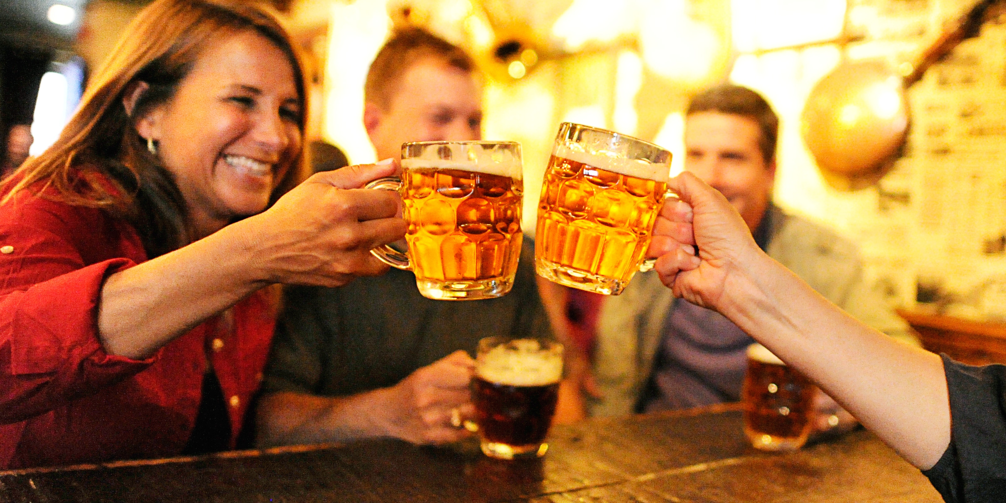 Two couples drinking beer in steins, with a woman toasting another woman