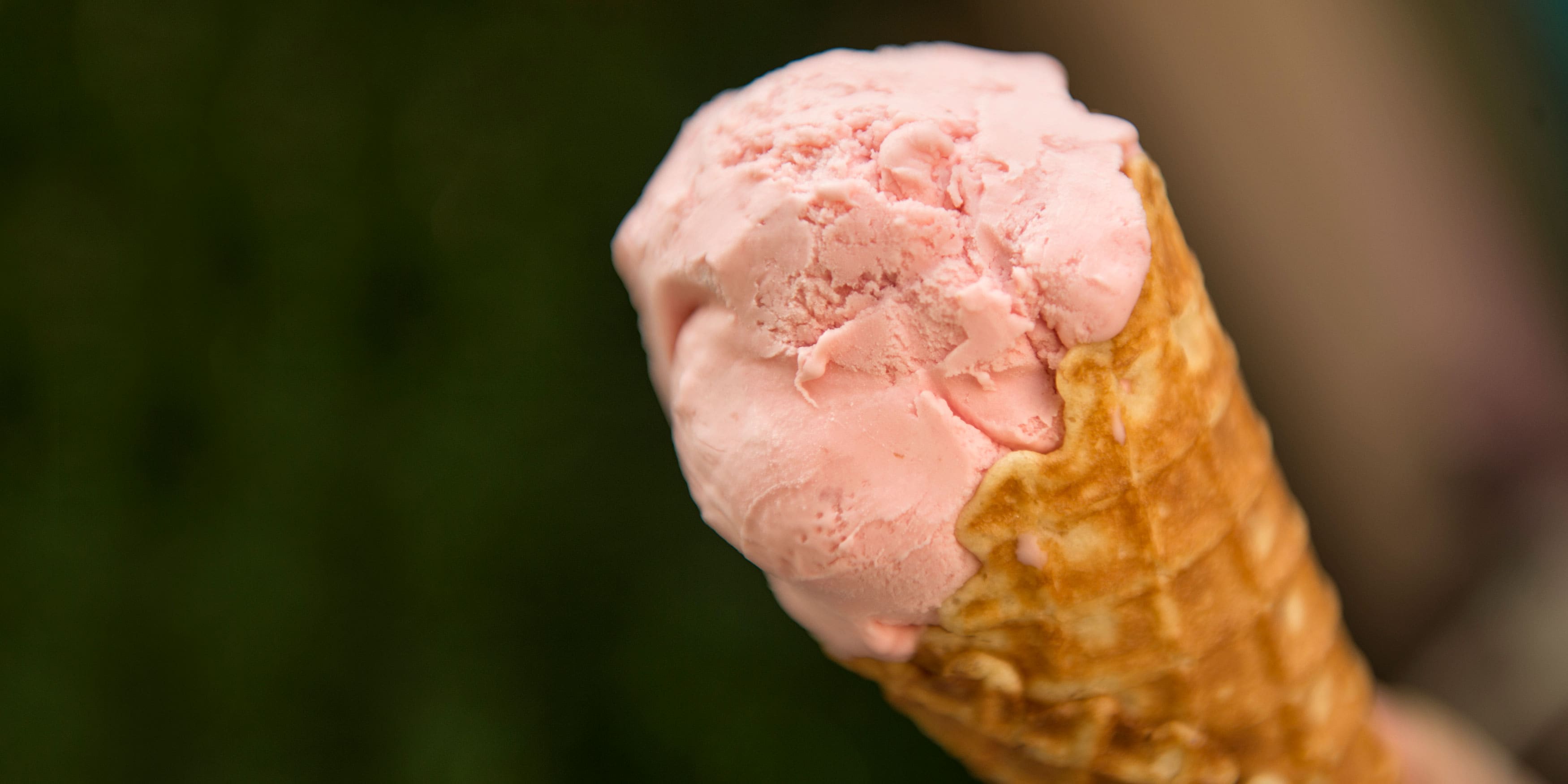 A scoop of strawberry ice cream inside a waffle cone