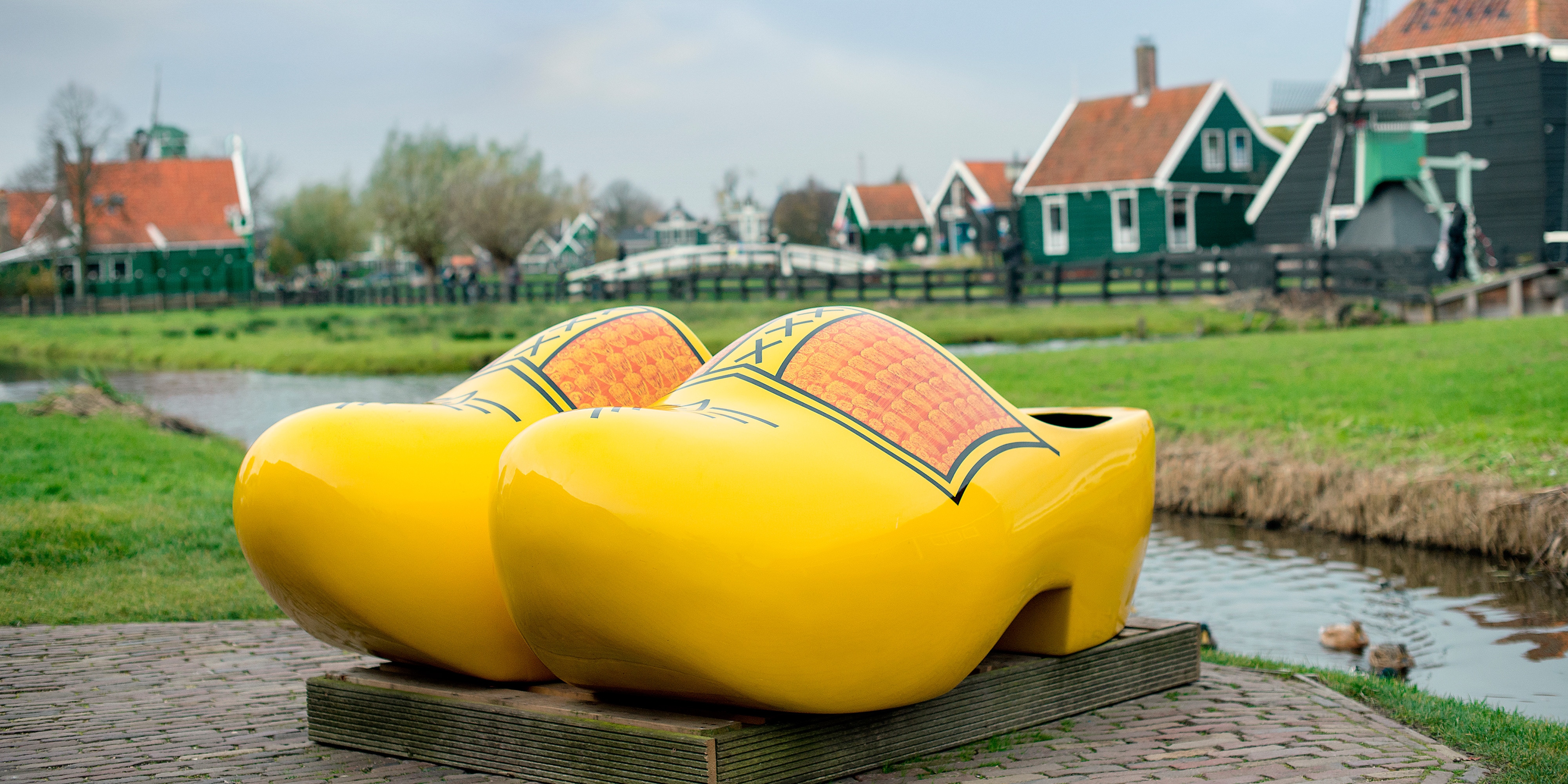 A pair of painted wooden clogs with several windmills in the background