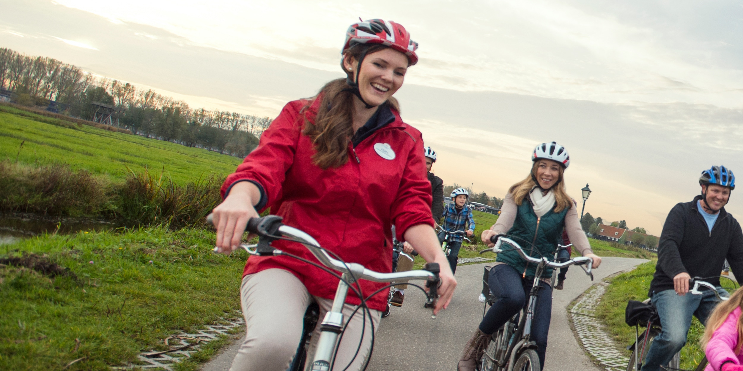 A female Adventure Guide and several Guests wearing helmets, bike along a path in Rüdesheim
